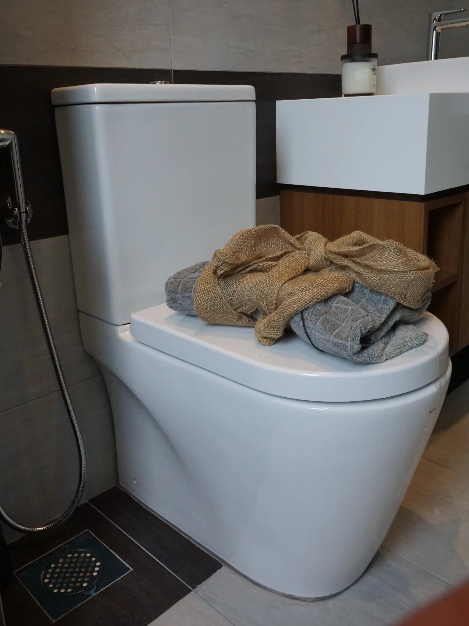 Bathroom floor trap set into a dark tiled wet zone, with the floor falling towards it. 